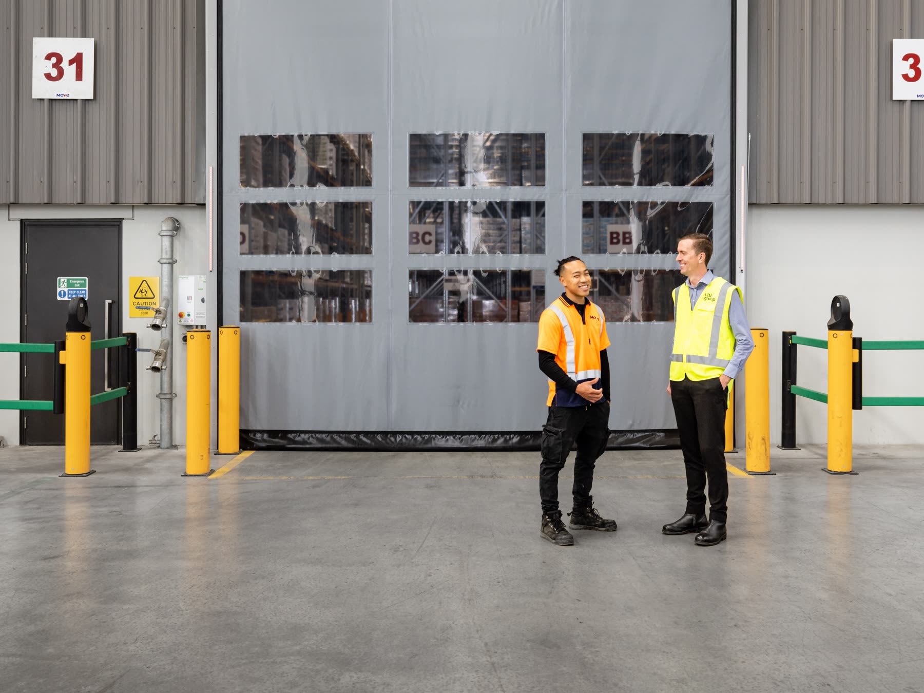 Refrigerated logistics warehouse at dusk with an insulated high-speed door open and a truck backed into a dock seal